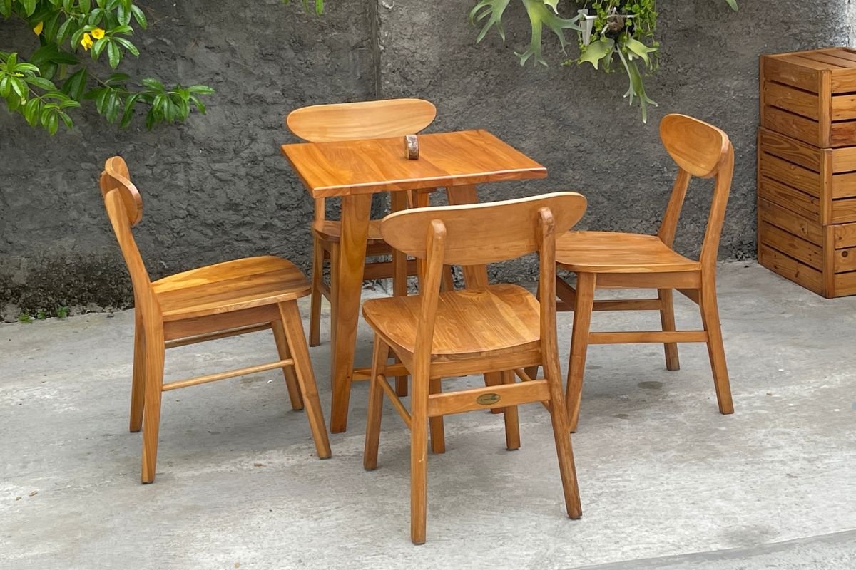 A wooden table with four chairs arranged outdoors, showcasing a cozy furniture service setup for outdoor dining.