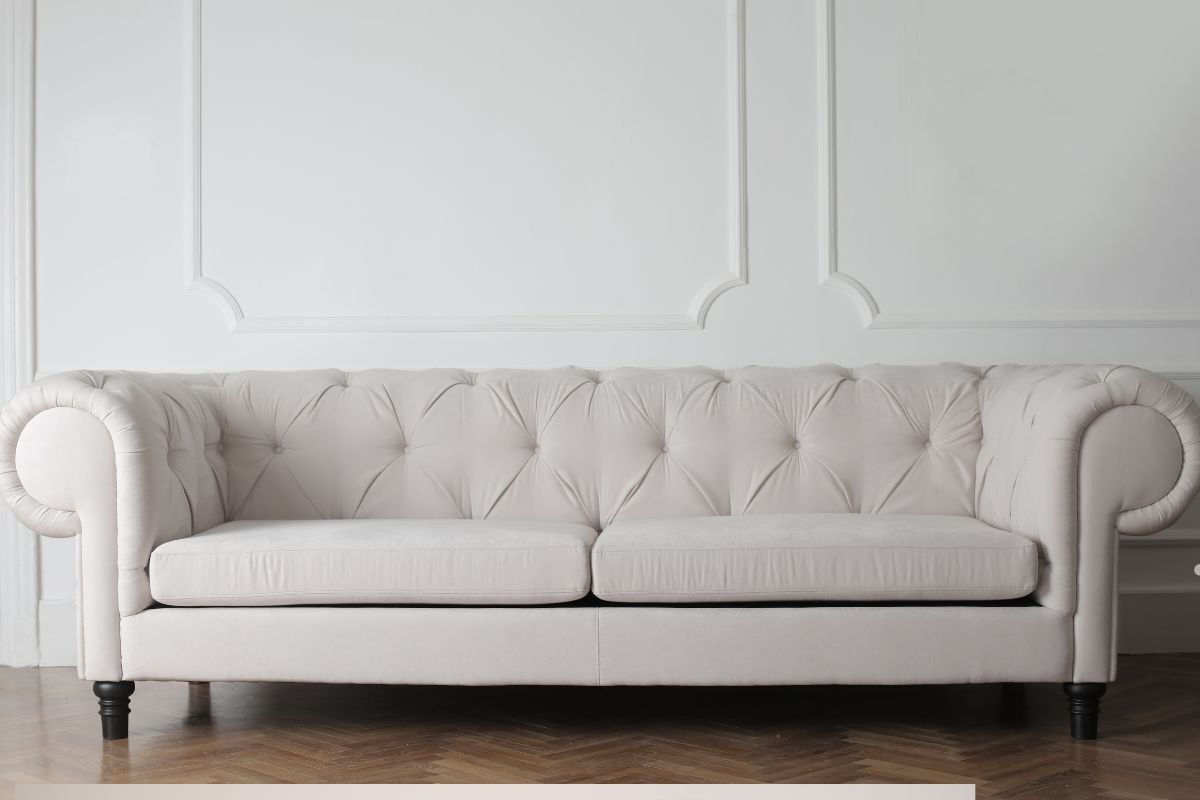 A white couch positioned against a white wall, showcasing its clean lines and modern design, ideal for furniture repair.